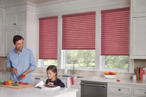 Child sitting at in the kitchen with windows that has Sonnette Cellular Roller Shades installed