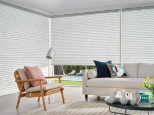 Living room with a couch and chair and windows have Sonnette Cellular Roller Shades installed