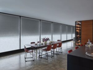 Dining room with wrap around windows that has Sonnette Cellular Roller Shades installed