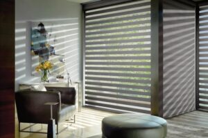 Living room with a chair and ottoman and floor to ceiling windows with Designer Banded Shades installed