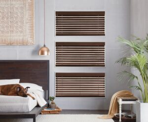 Bedroom with dog on the bed near windows with Parkland Wood Blinds installed