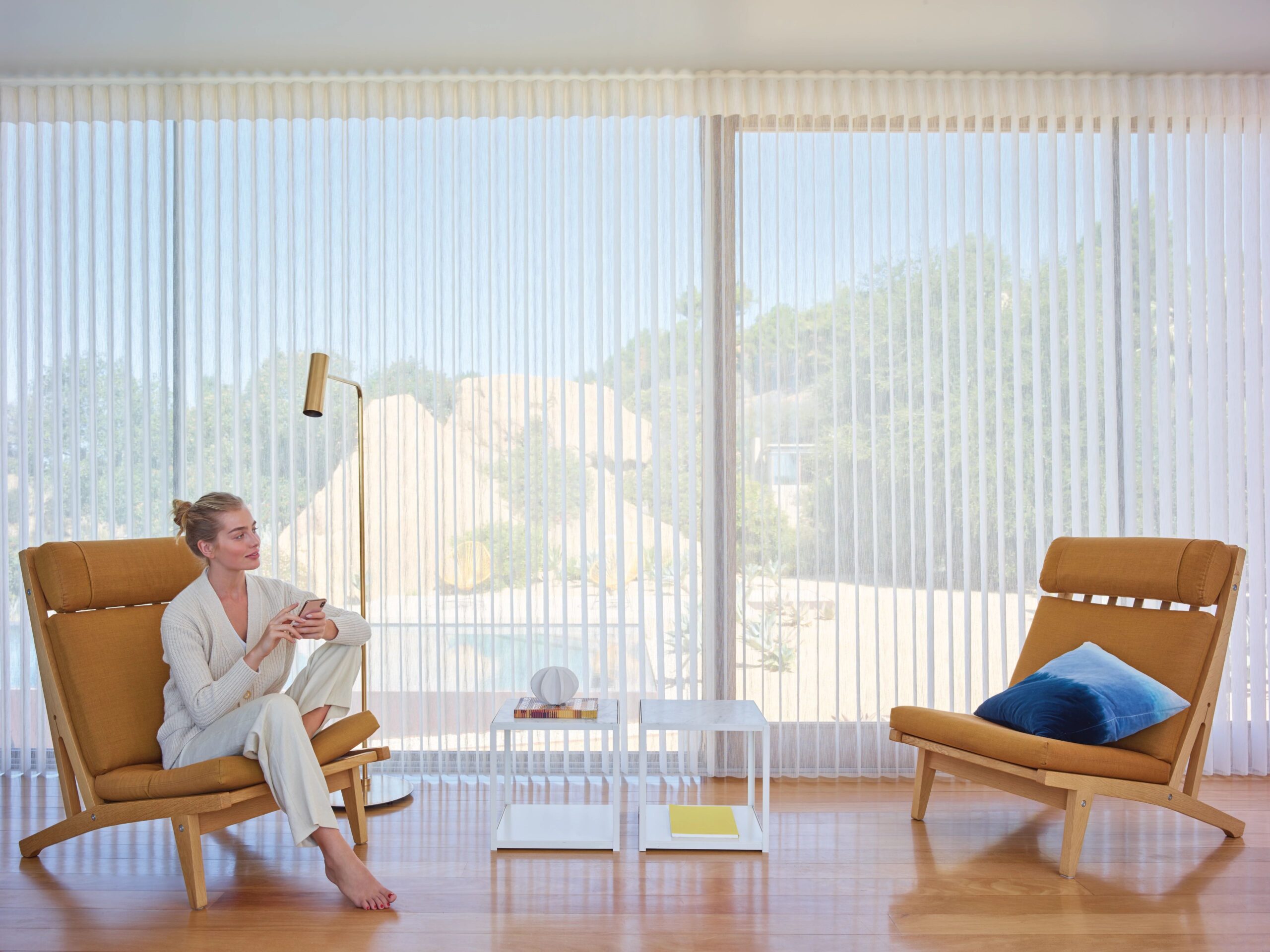 Woman sitting in chair in living room with Luminette Sheer Shades
