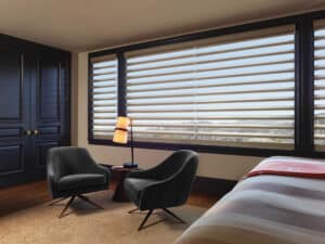 Twon chairs and a bed in bedroom with windows covered with Pirouette® Sheer Shades