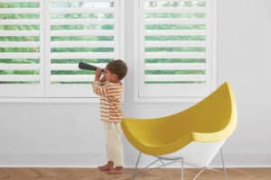 Child in playroom with windows covered with NewStyle Hybrid Shutters