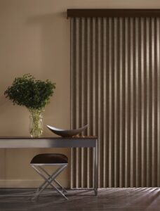 Dark coloured hall way with table and stool near window with Cadence Soft Vertical Blinds installed