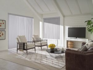 Living room with dark couch and two light chairs and windows with Cadence Soft Vertical Blinds installed