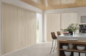 Kitchen with island and two stools and patio doors with Cadence Soft Vertical Blinds installed