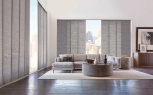 Living room with sectional and coffee table with windows covered with Skyline Gliding Window Panels
