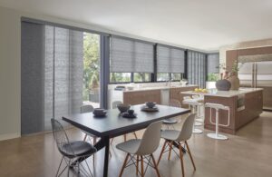 Kitchen with table and an island and windows covered with Skyline Gliding Window Panels