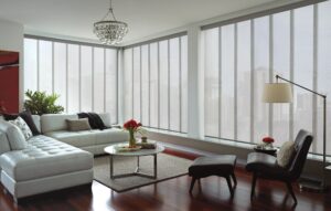 Living room with sectional and a chair with windows covered in Skyline Gliding Window Panels