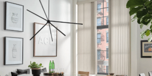 Dining room with designer chandalier with a corner window with Cadence Soft Vertical Blinds installed