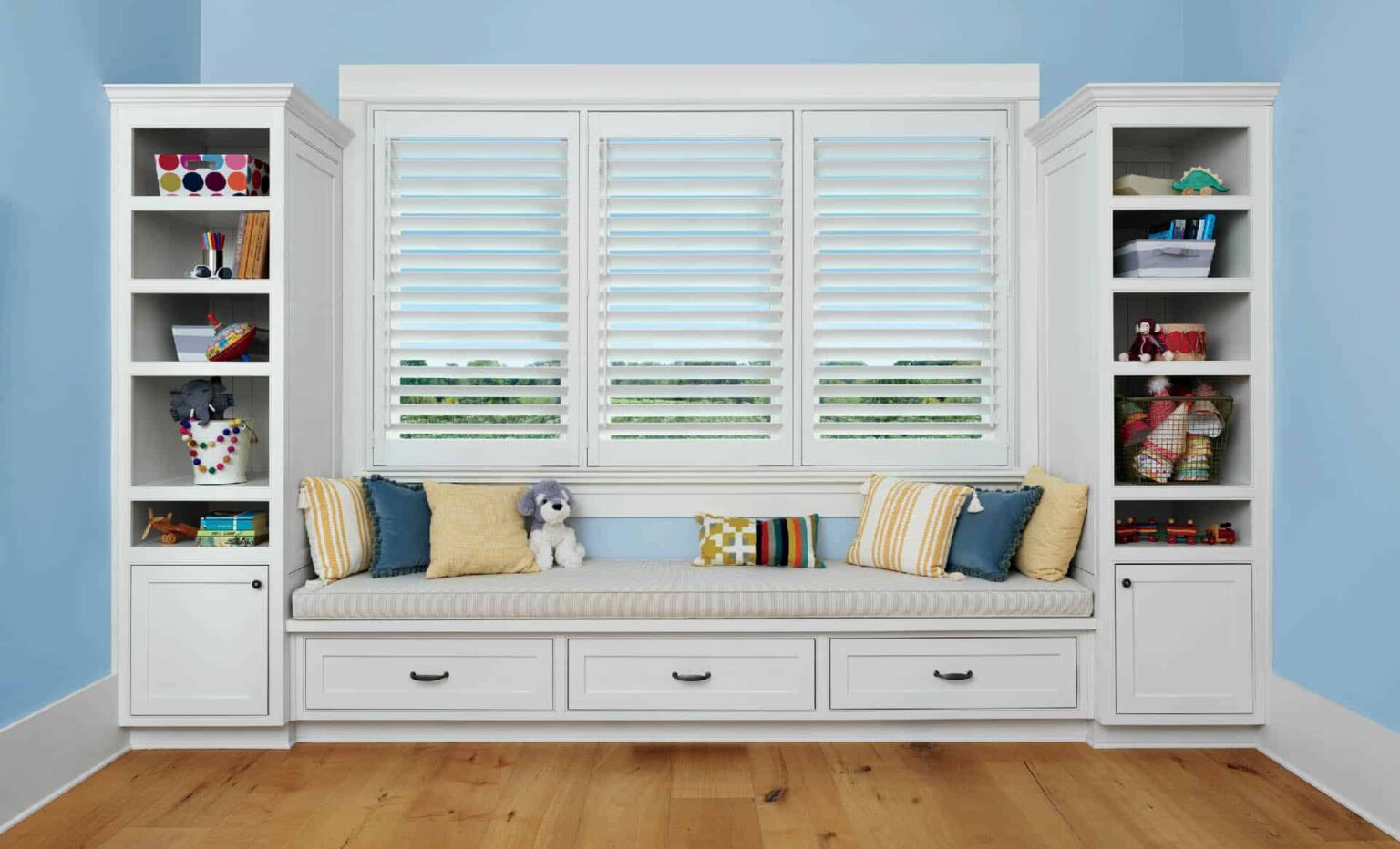 A child's room with a window seat and bookshelves.