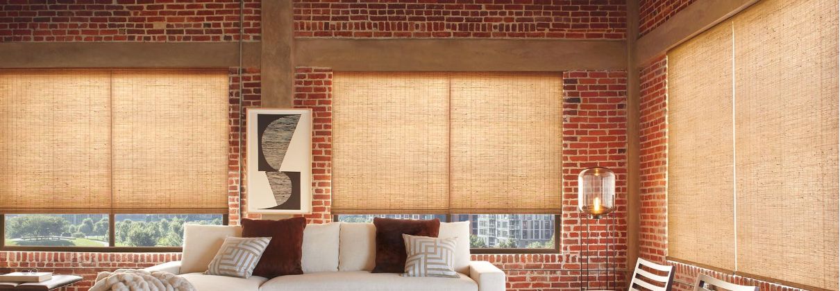 A living room with brick walls and bamboo shades.