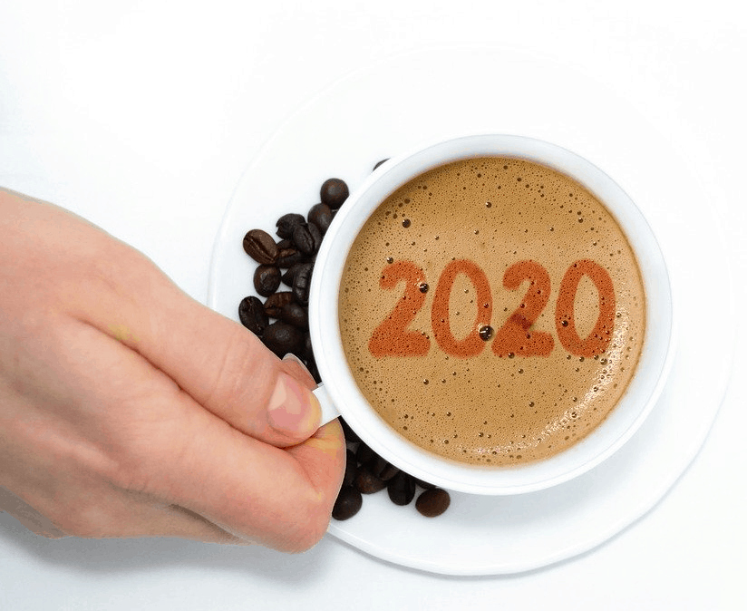 A person holding a cup of coffee with the word 2020 written on it.