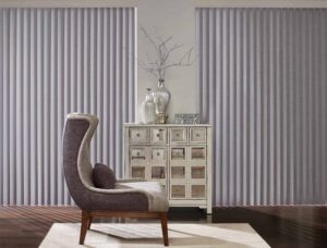 Vertical blinds in a living room with a chair, featuring Hunter Douglas Cadence Vertical Blinds.