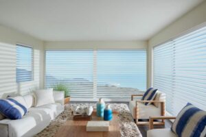 A living room with sheer shades and a view of the ocean.