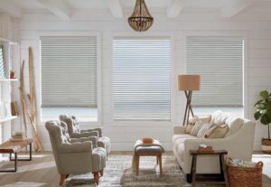 A living room with white furniture and venetian blinds.