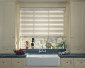 A kitchen with a sink and venetian blinds.