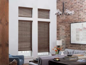 A living room with venetian blinds and a brick wall.