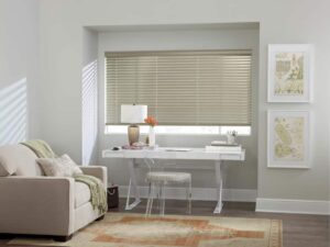 A room with a desk, chair and venetian blinds.