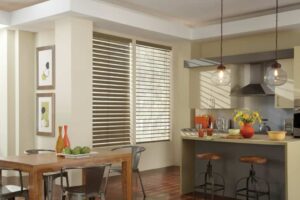 A kitchen with venetian blinds on the windows, a dining table, and chairs.