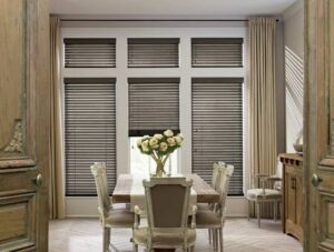 A dining room with venetian blinds and a wooden table.