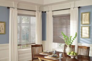 A dining room with venetian blinds and a wooden table.