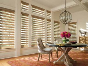 A dining room with wooden blinds and sheer shades.