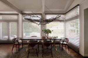 A dining room with a wooden table and chairs, adorned with stylish sheer shades.