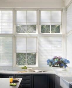A kitchen with black cabinets and white sheer shades.