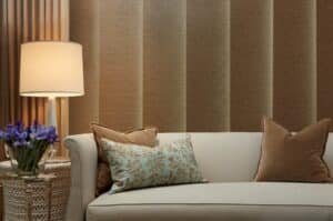 A living room with a brown couch, a lamp, and Hunter Douglas Skyline blinds.