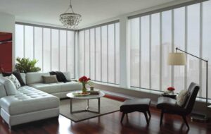 A living room with white furniture and large windows, featuring Hunter Douglas Skyline blinds.